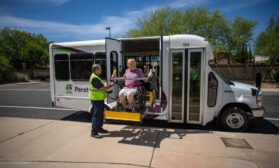 a woman in a wheelchair gets out of a mini bus