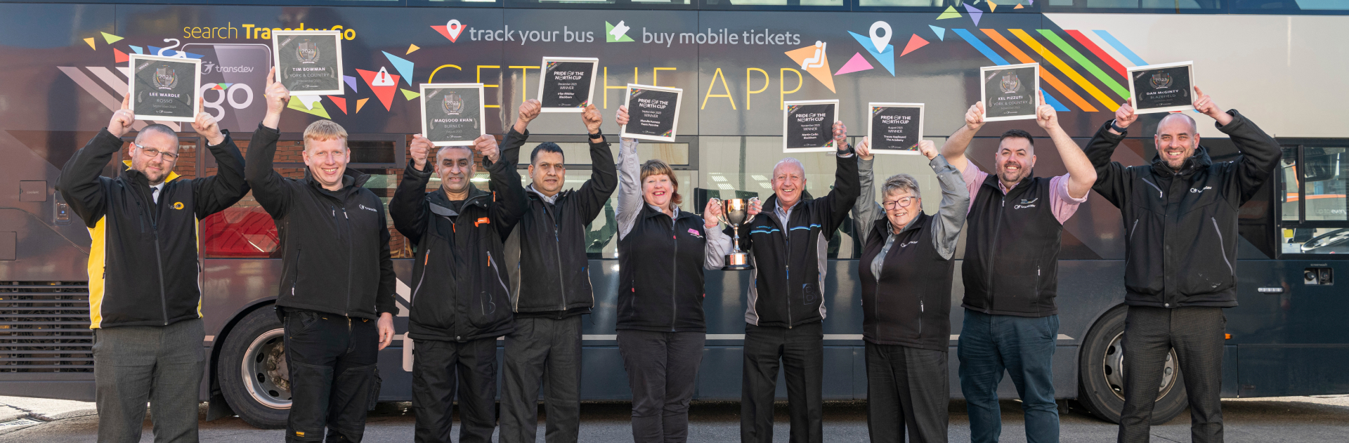 Transdev UK drivers standing in front of a bus an holding diplomas